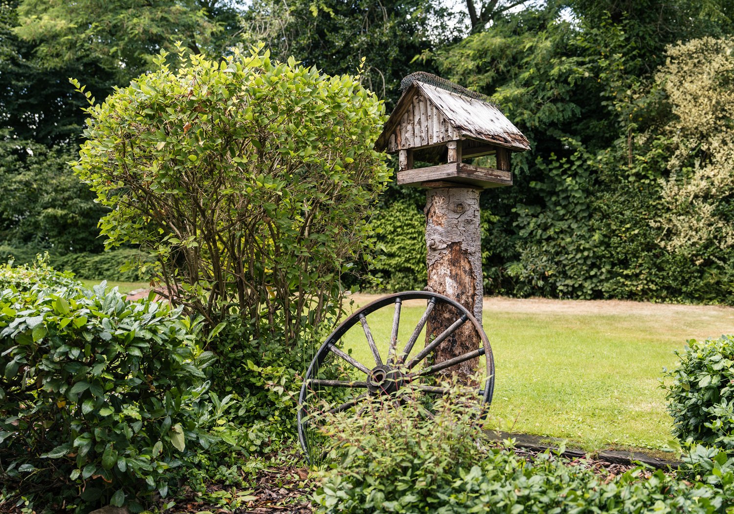 Garten mit Vogelhaus und altem Wagenrad