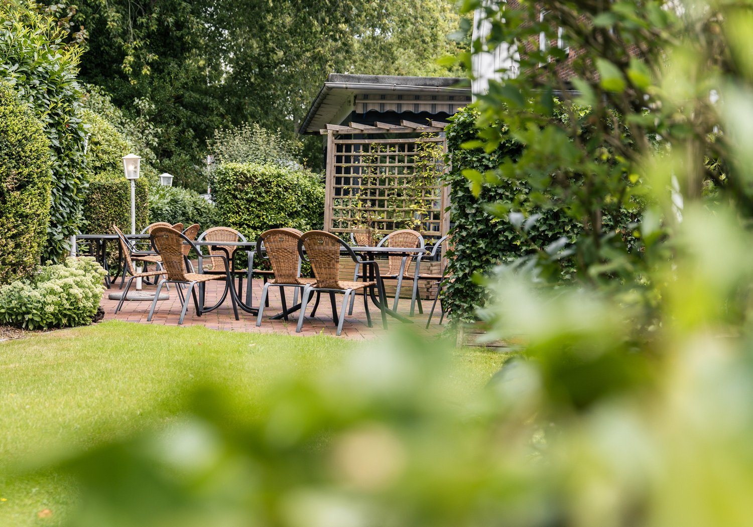 Gartenterrasse mit Tischen und Korbstühlen