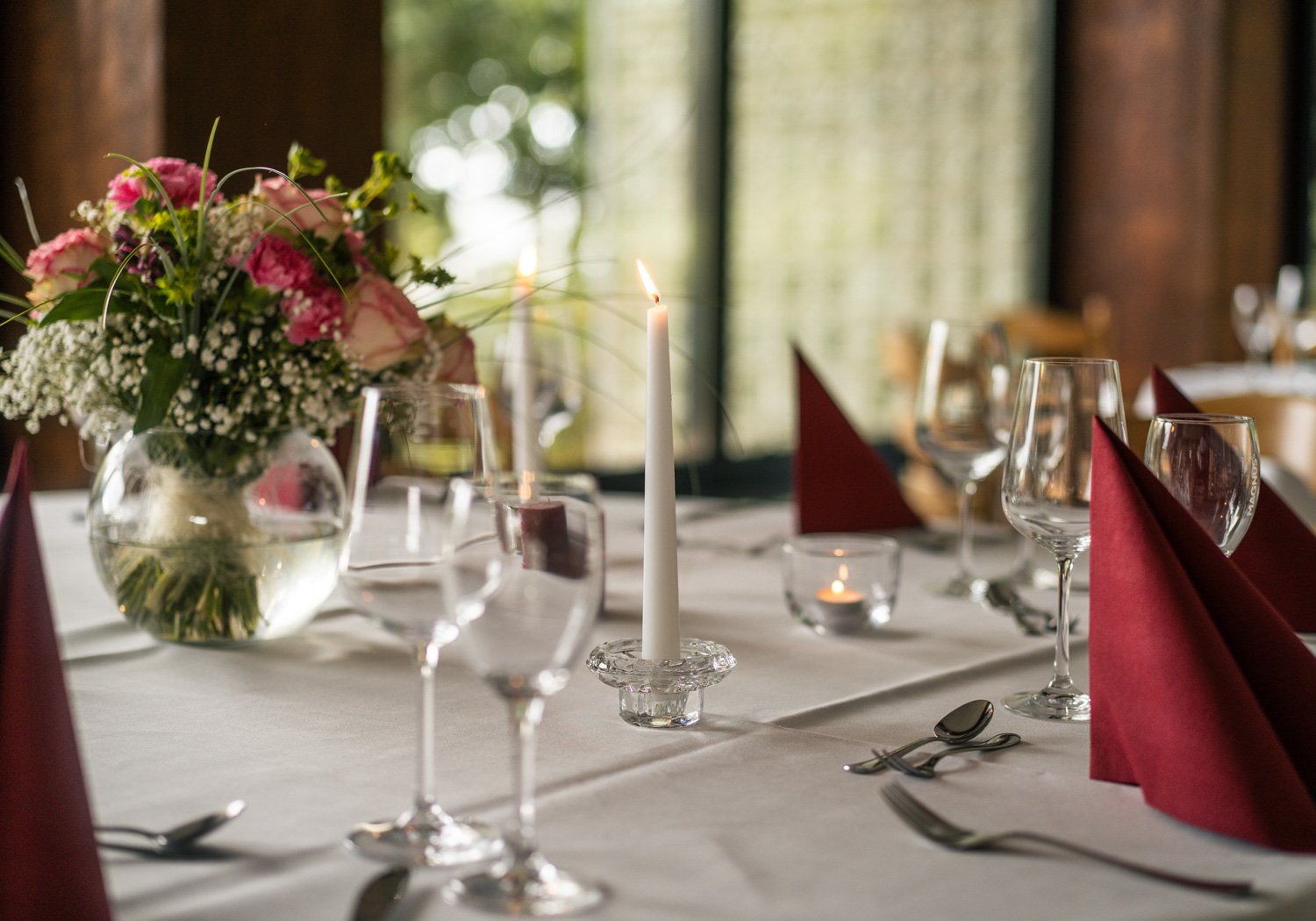 Festlich gedeckter Tisch mit Blumen, Kerzen und roten Servietten