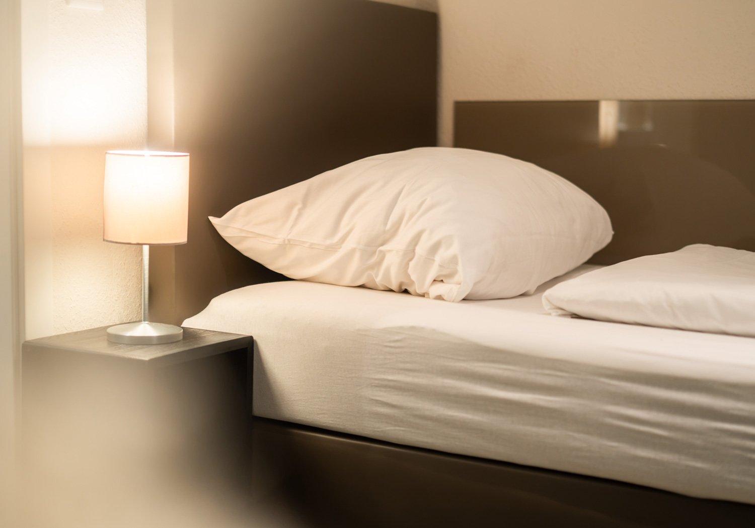 Hotelbett mit gepolstertem Kopfteil und Leselampe