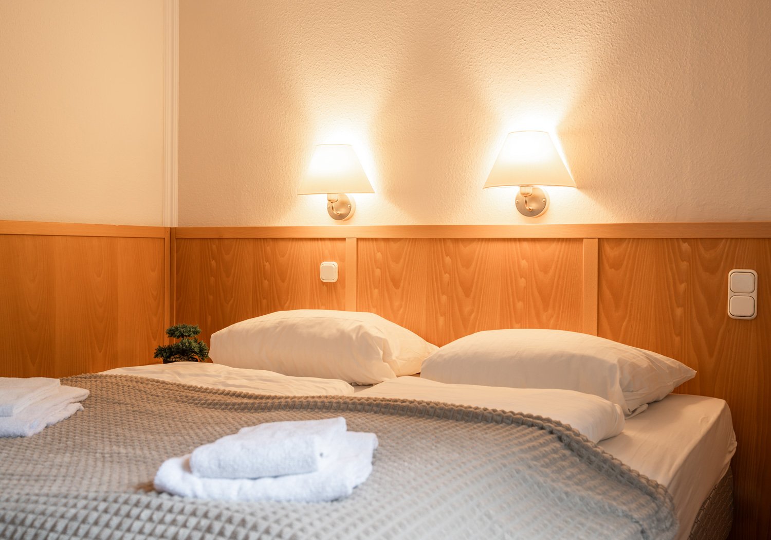 Doppelbett mit Holzvertäfelung und warmen Wandleuchten