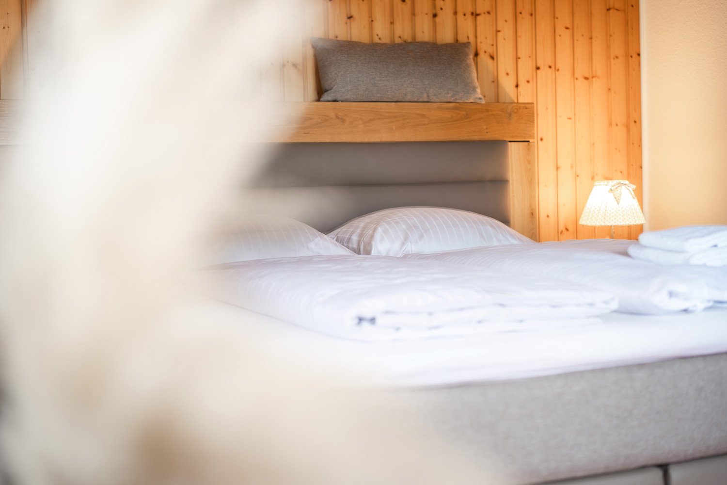 Gepolstertes Hotelbett vor einer Holzwand