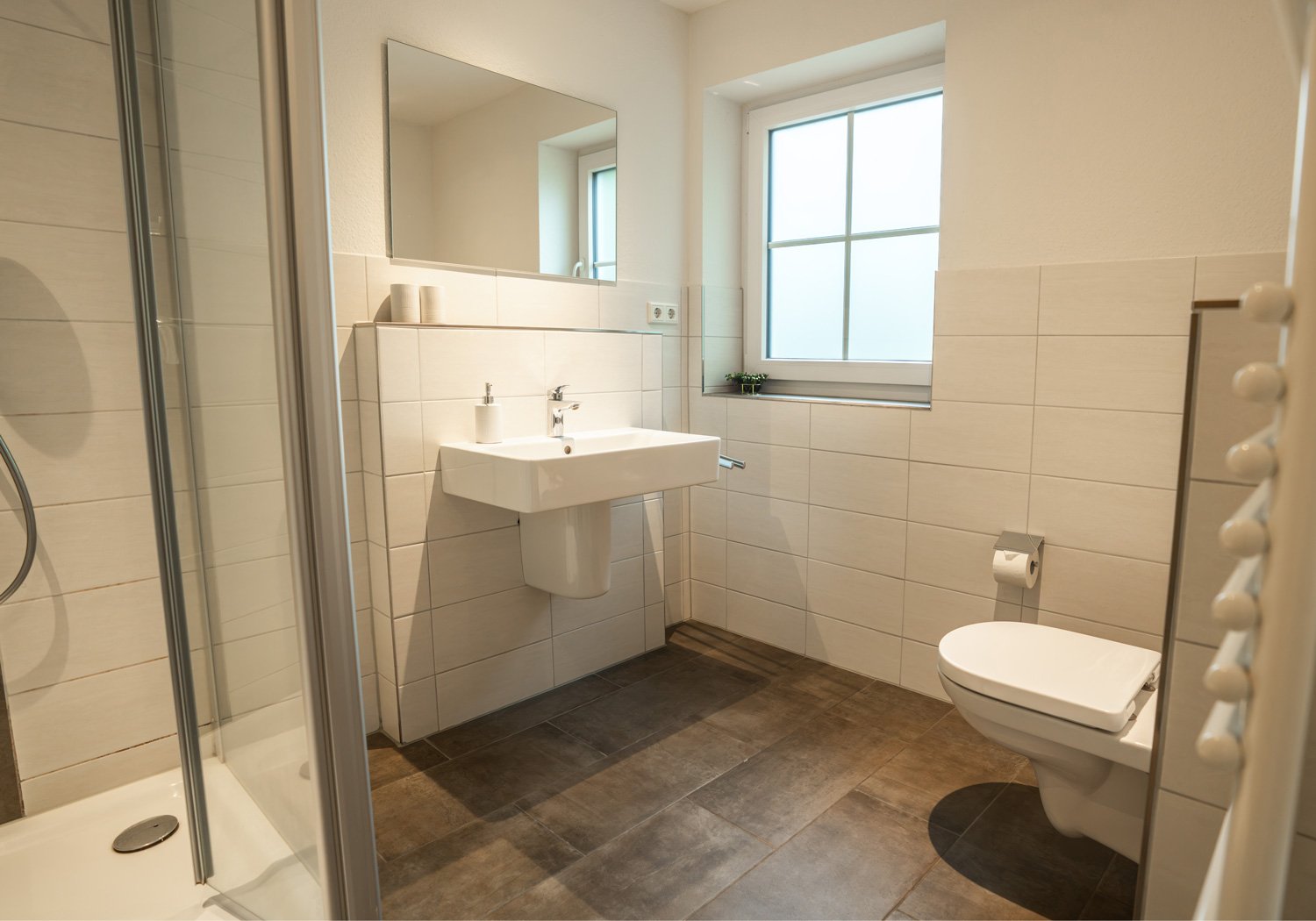 Badezimmer mit Dusche, Waschbecken und Fenster