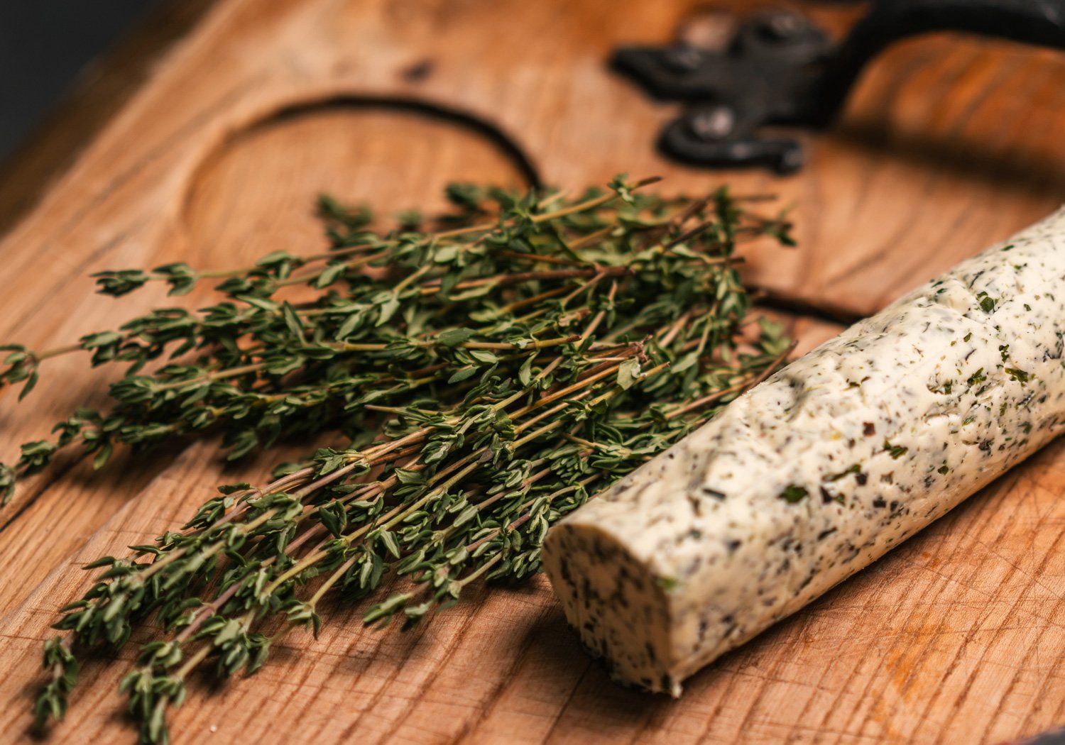 Kräuterbutter und frischer Thymian auf einem Holzbrett